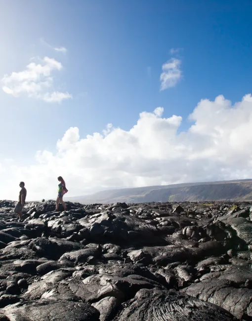 woman walking along a black lava field