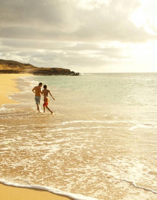 A couple walking on an empty beach on Molokai