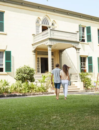 Historic Hulihee Palace, a white colonial-style building with a green lawn and palm trees in Kailua-Kona.