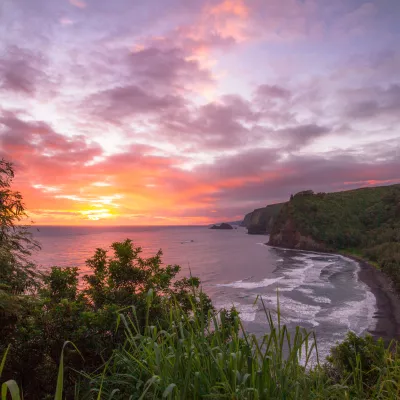 Scenic view from Pololu Valley Lookout at sunset, overlooking a lush valley, black sand beach, and the northeastern coastline.