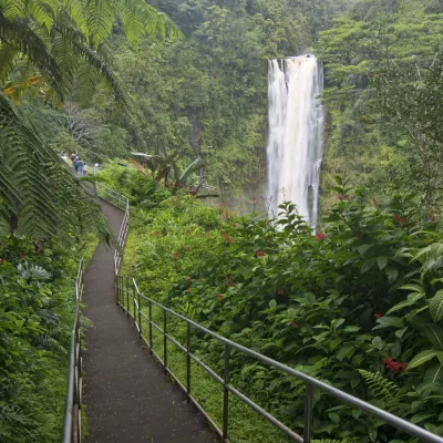 A paved path surrounded by lush greenery leading to the majestic Falls.