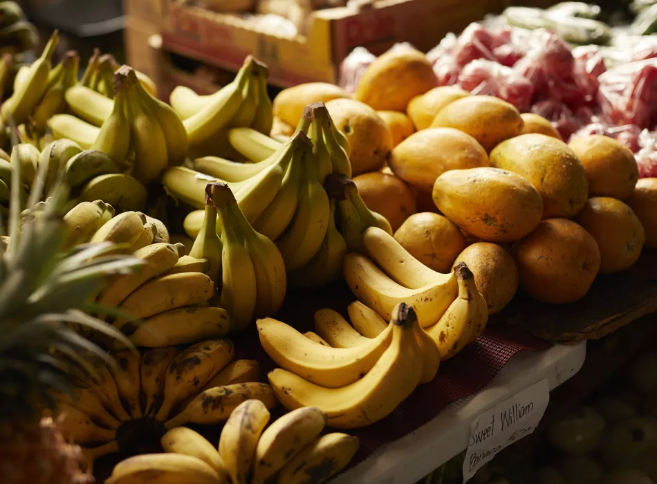 Close-up of fresh bananas and papayas displayed at the Hilo Farmers Market, surrounded by other fruits and produce.