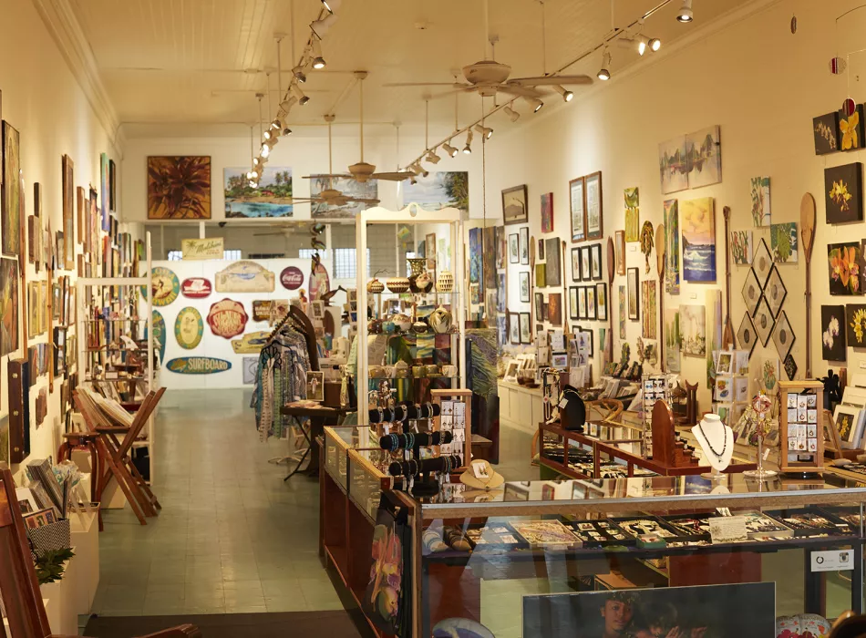 Interior of an art gallery and shop showcasing colorful paintings, jewelry, and locally crafted items on display.