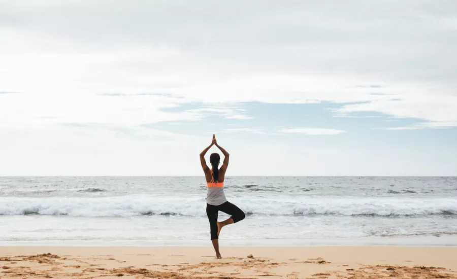 Woman practicing yoga on the beach